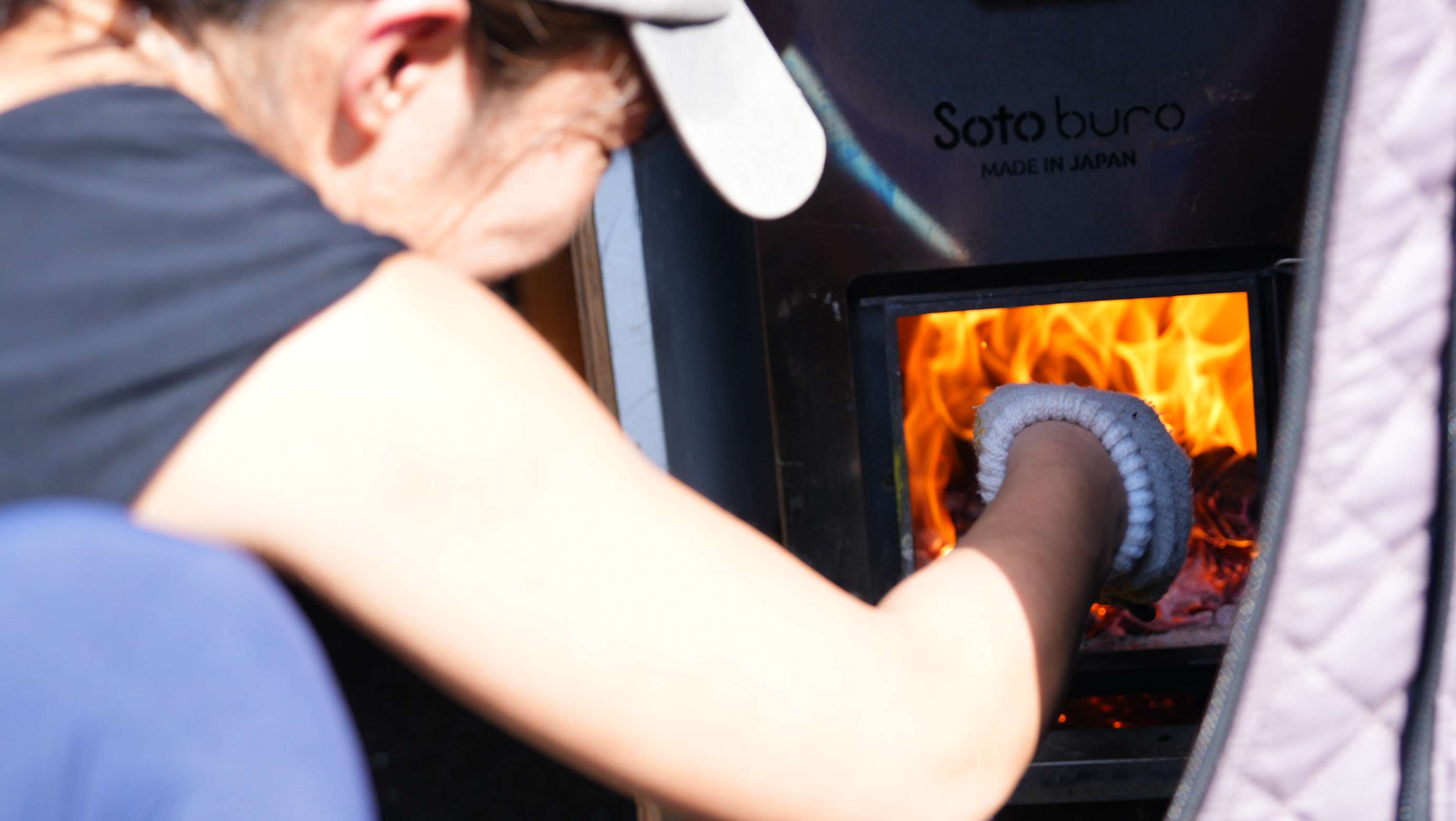 スタッフが焚き火に薪をくべる様子